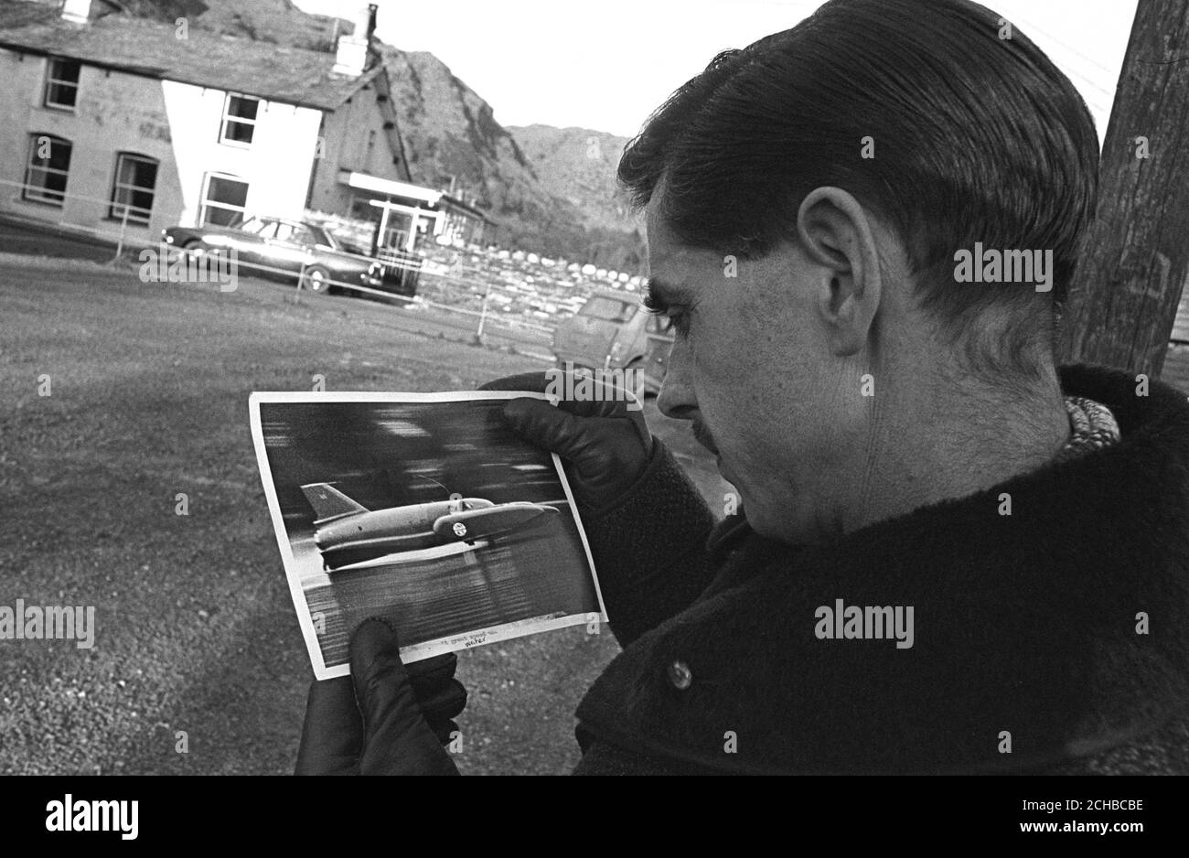 Ken Norris, concepteur principal de Bluebird, examine une photographie de l'aviateur de l'Association de presse, prise une fraction de seconde avant l'accident d'hier, au cours de laquelle Donald Campbell a été tué alors qu'il tentait de battre son propre record mondial de vitesse de l'eau. La photo montre le parrainage tribord du bateau propre de l'eau. Banque D'Images