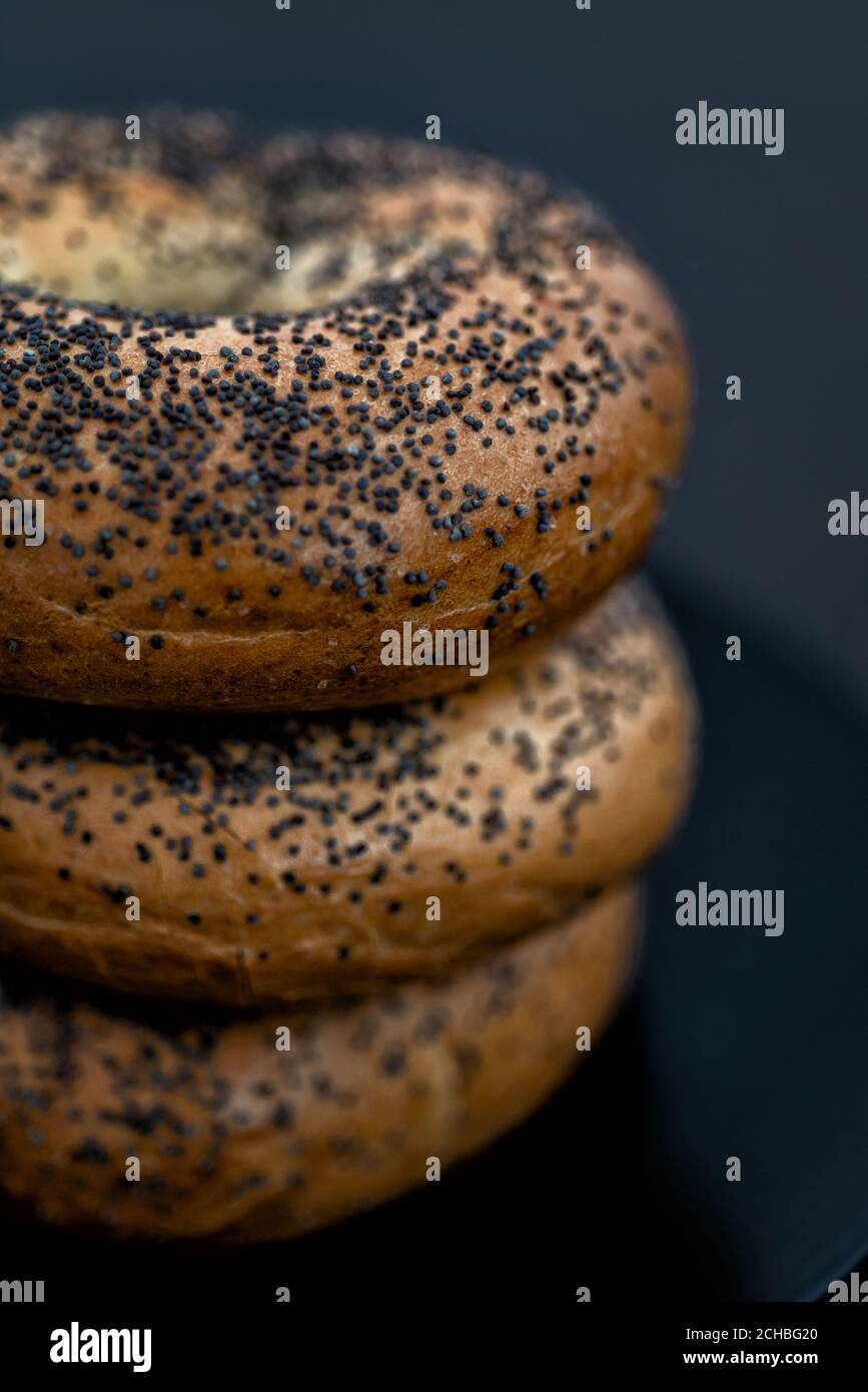 Assiette noire pleine de bagels sur fond noir Banque D'Images
