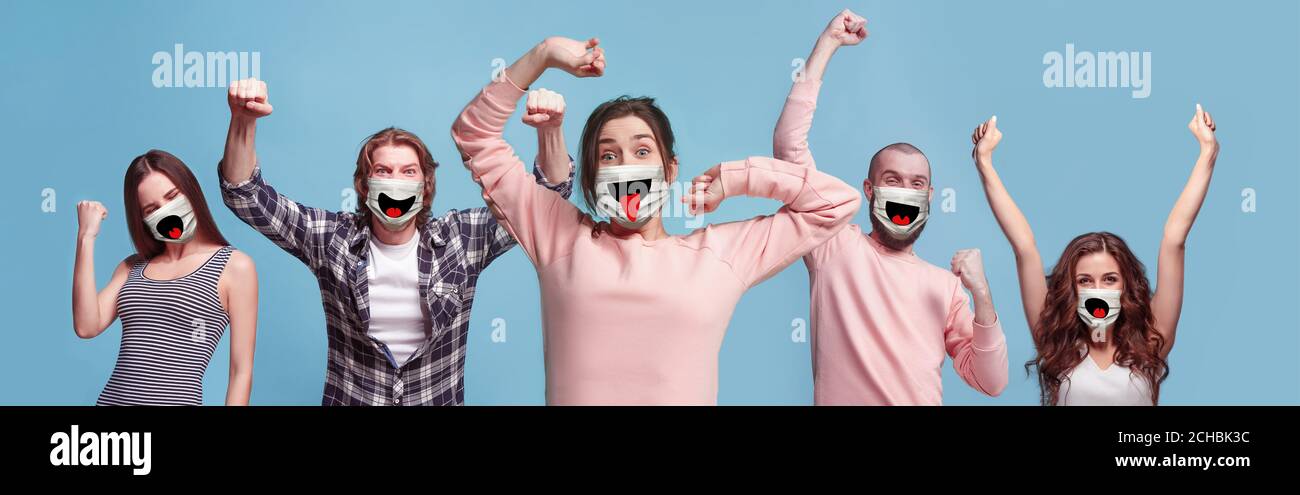 Groupe de personnes gagnantes et heureuses, femmes et hommes portant un masque facial protecteur sur fond bleu. Modèles multiraciaux. Collage. Concept des émotions humaines, expression faciale, sécurité, protection. Banque D'Images