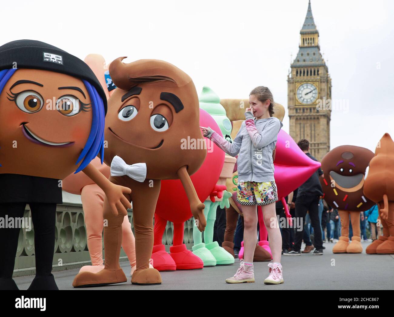 EDITORIAL UTILISEZ SEULEMENT Freya Bowes, 12 ans, avec des personnages du film Emoji lorsqu'ils se promeuissent sur le pont de Westminster à Londres avant la Journée mondiale Emoji le 17 juillet. Banque D'Images