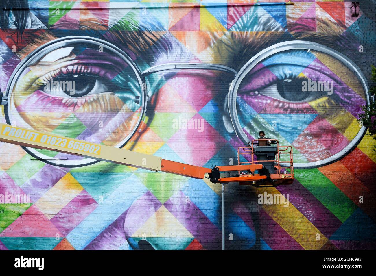 Un graffiti travaille sur une énorme fresque de John Lennon lorsqu'il participe à l'Upfest, un festival d'art de rue et de graffiti à Bristol. Banque D'Images