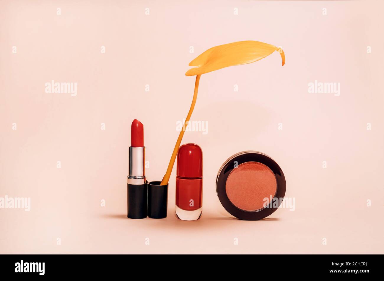 Composition décorative avec cosmétiques, produits de beauté pour femmes, rouge à lèvres, fard à joues et vernis à ongles, décorée de feuilles jaunes d'automne sur fond clair, mode encore-vie Banque D'Images