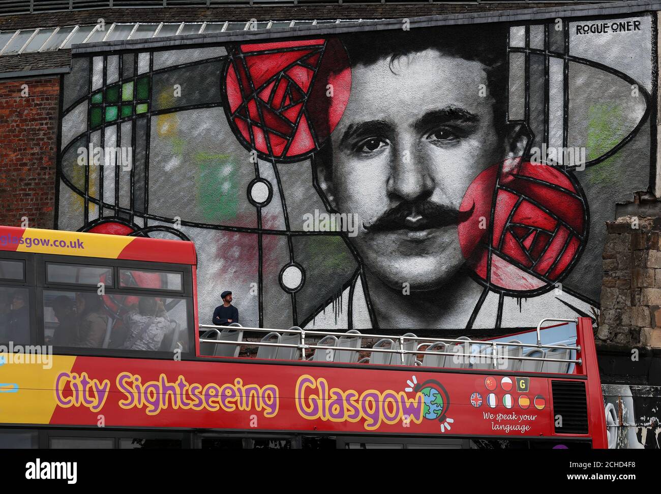 Artiste Bobby McNamara connu sous le nom de Rogue-un point de vue son travail à son inauguration en tant que Glasgow tour bus passe le street art mural géant dédié à Charles Rennie Mackintosh peint sur un grand mur donnant sur la Clutha bar à Glasgow. Banque D'Images