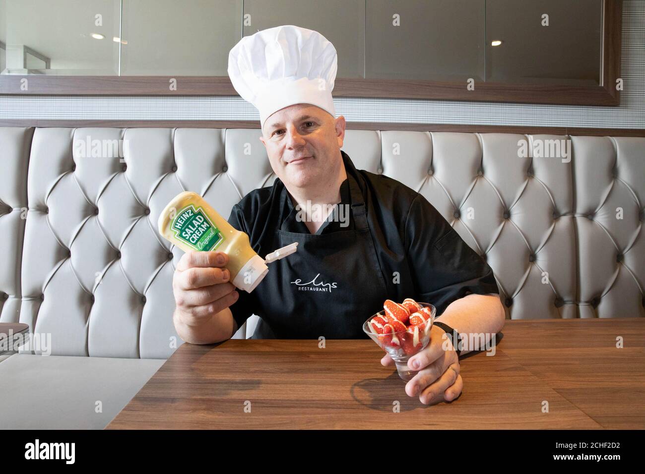 UTILISATION ÉDITORIALE SEULEMENT le chef de cuisine Bernado Grarea du grand magasin indépendant de Wimbledon Elys ajoute la touche finale à son plat, à ses fraises et à sa crème à salade Heinz, une touche d'originalité sur un classique britannique créé pour marquer le début de la saison de tennis de Wimbledon. Banque D'Images