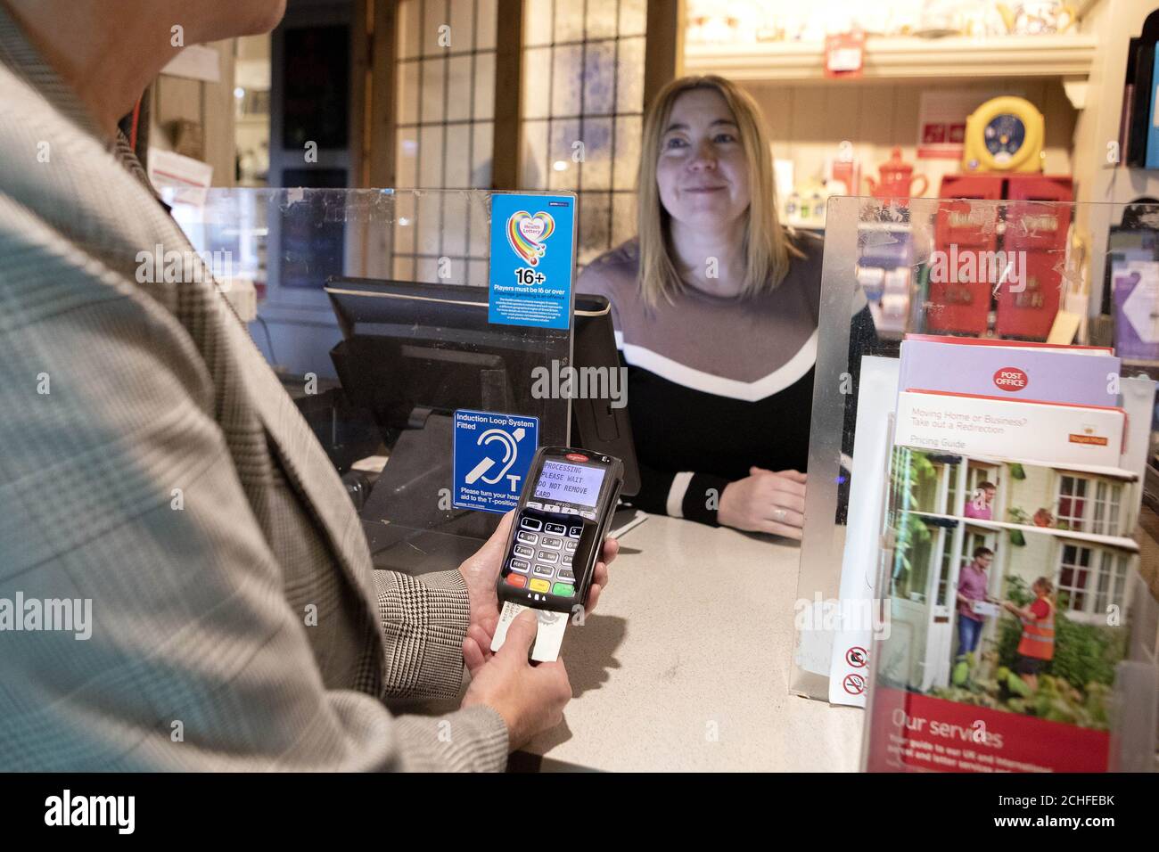Un client retire de l'argent au bureau de poste de Bamford, Derbyshire, Géré par la postmistress Sarah France et situé dans le pub Anglers Rest, le bureau de poste annonce un nouvel accord avec 28 banques britanniques pour garantir à des millions de personnes à travers le pays un accès libre aux services bancaires quotidiens. Banque D'Images