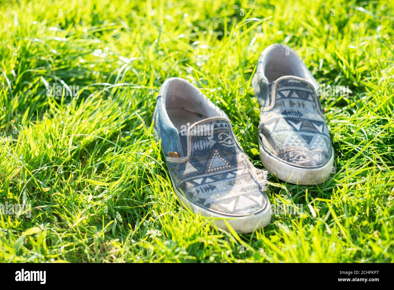 Des chaussures en plimsoll bien portées sur l'herbe pendant un été chaud jour Banque D'Images