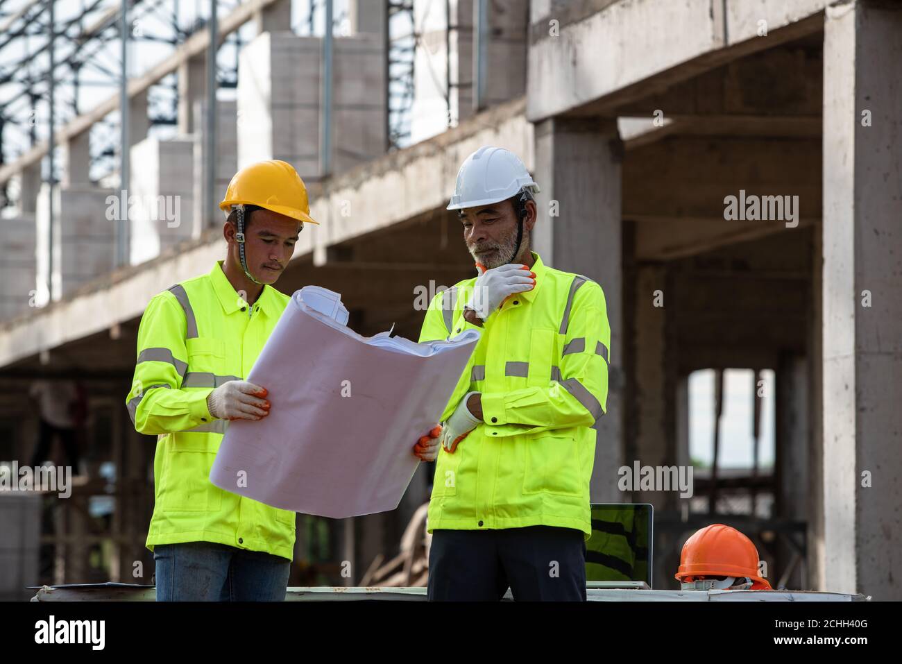 Les superviseurs Engineering Reading Blueprint sur le chantier de construction Banque D'Images