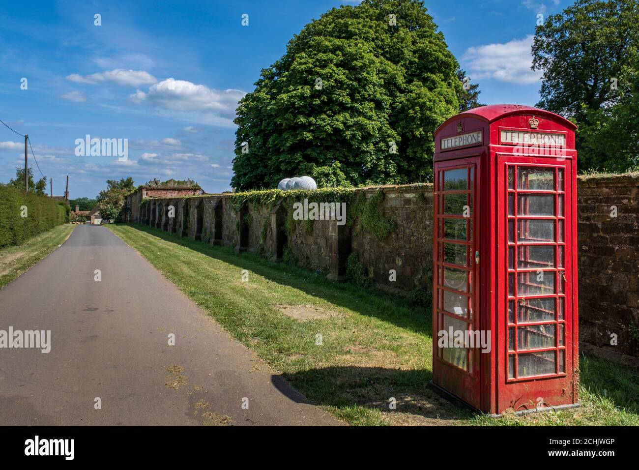 Une boîte téléphonique rouge dans le joli hameau de Nevill Holt, à côté du parc de Nevill Holt Hall, Leicestershire, Angleterre, Royaume-Uni Banque D'Images