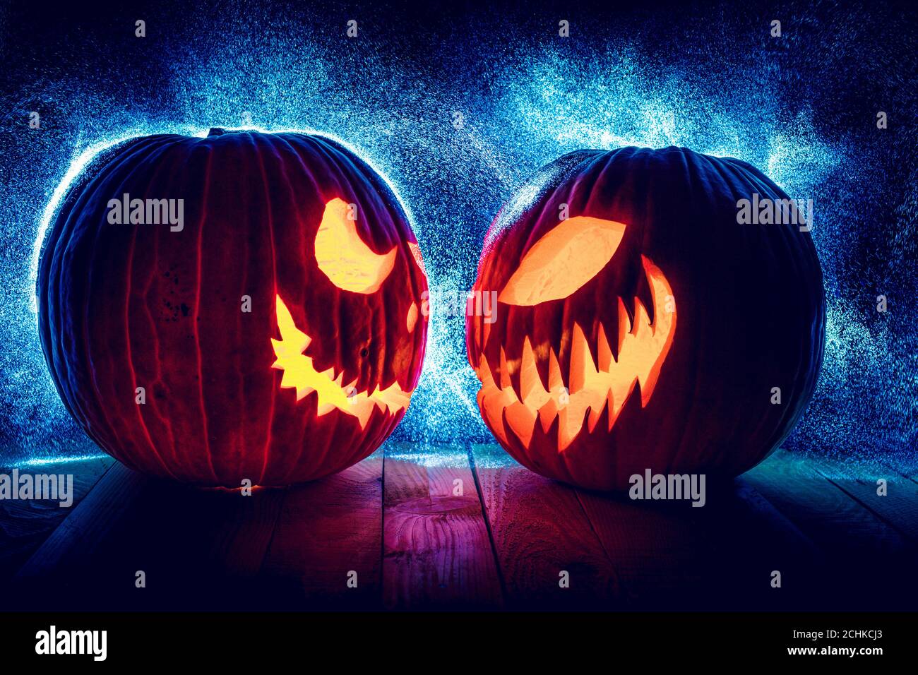 citrouilles d'halloween en face l'une de l'autre sur fond noir avec des lumières à pois en arrière-plan. Banque D'Images