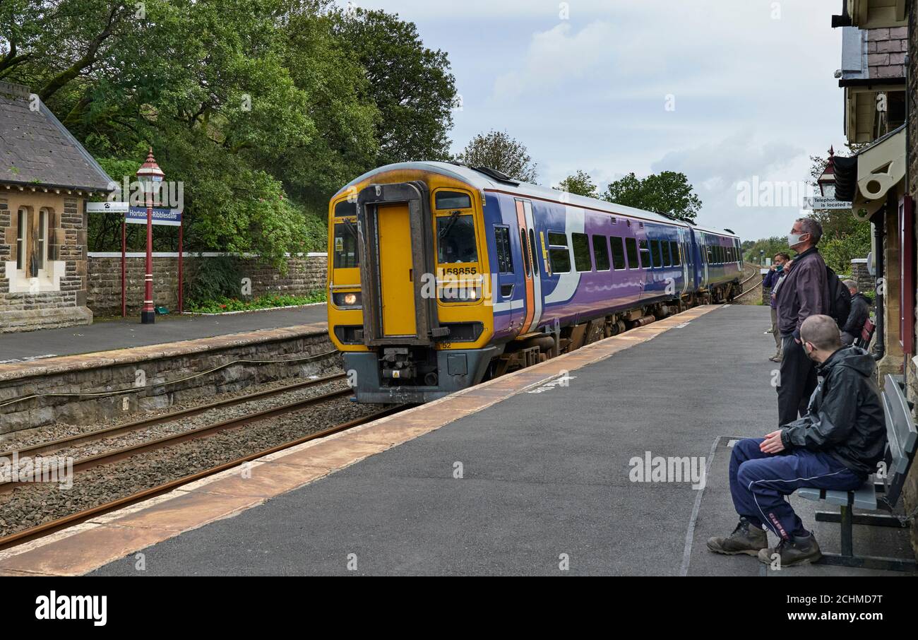 Les passagers portant des masques observant l'arrivée du service de chemin de fer du Nord à Leeds à 48:17, sur la plate-forme de Horton en direction du sud, à la gare de Ribblesdale. Banque D'Images
