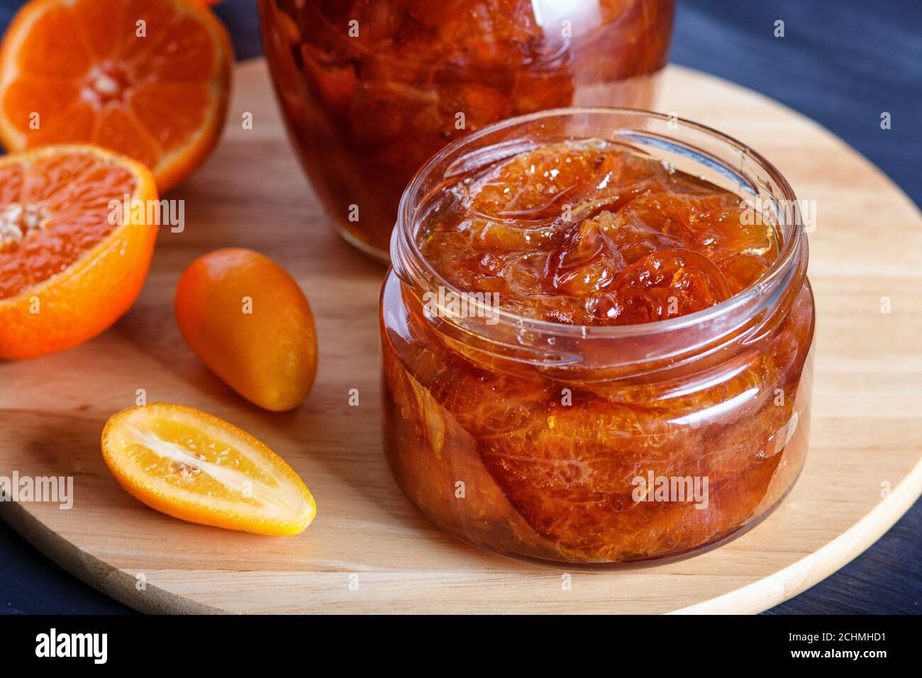 Confiture de mandarine et de kumquat dans un pot en verre avec des fruits frais sur une table en bois noir. Maison, gros plan. Banque D'Images