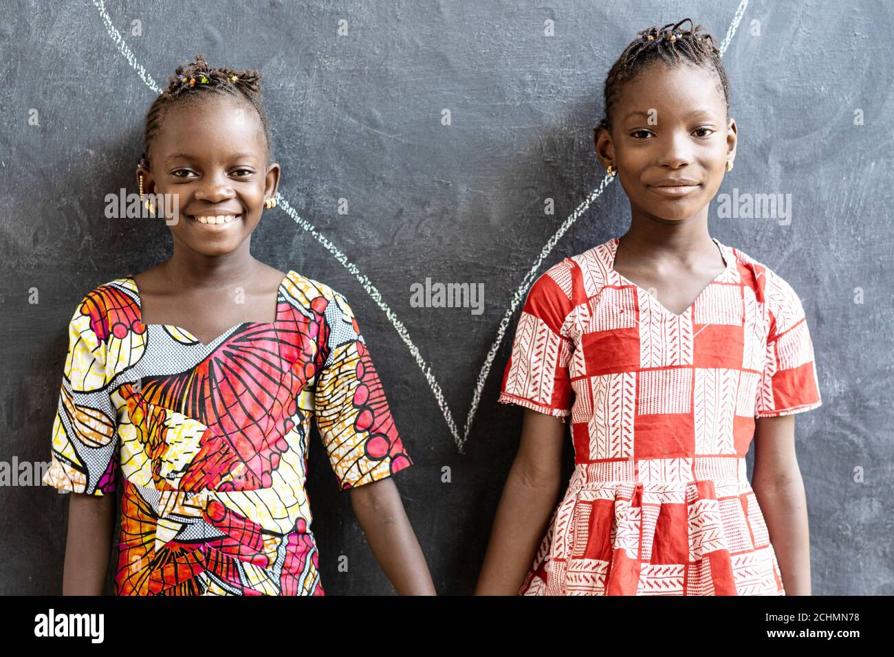 De magnifiques sœurs africaines posant, souriant et riant heureux devant le Blackboard à l'école Banque D'Images