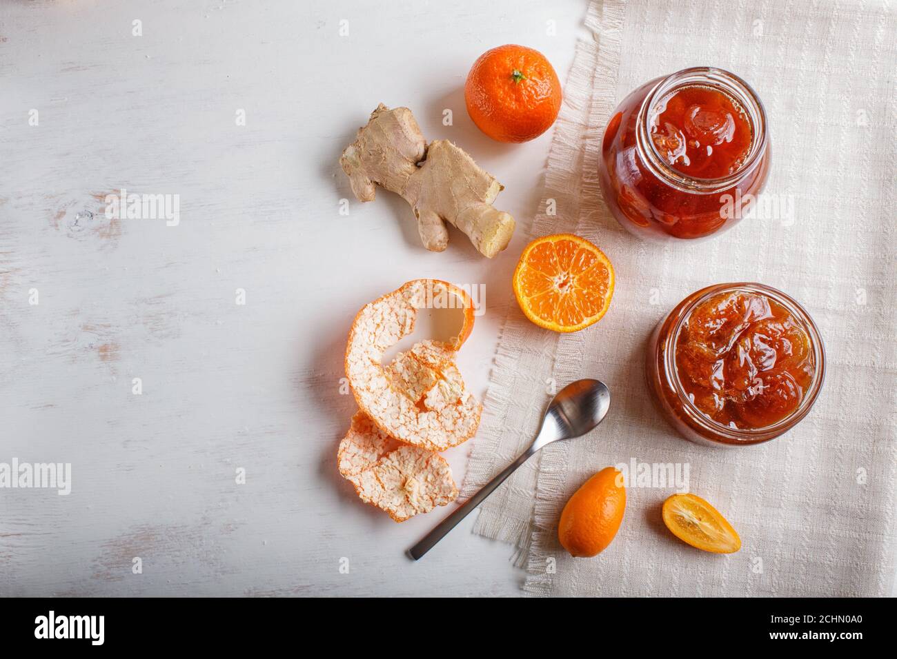 Confiture de mandarine et de kumquat dans un pot en verre avec fruits frais sur fond de bois blanc. Maison, espace de copie, vue du dessus. Banque D'Images