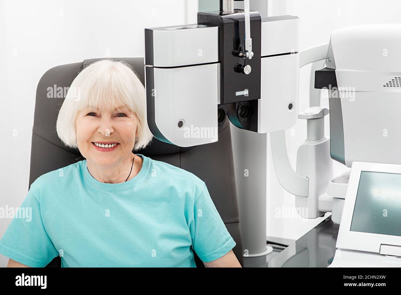 Vérifier la vue de la femme âgée souriante sur le phoropter moderne. Si une femme a une mauvaise vue, le médecin donnera une ordonnance pour des lunettes Banque D'Images