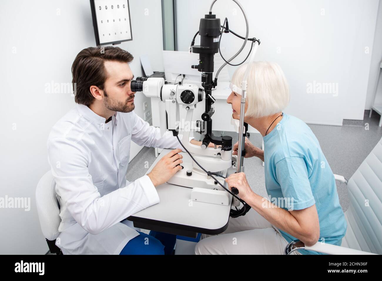 Optométriste concentré qui vérifie l'œil d'un patient à l'aide d'un équipement moderne. Examen oculaire et diagnostic de la vision Banque D'Images
