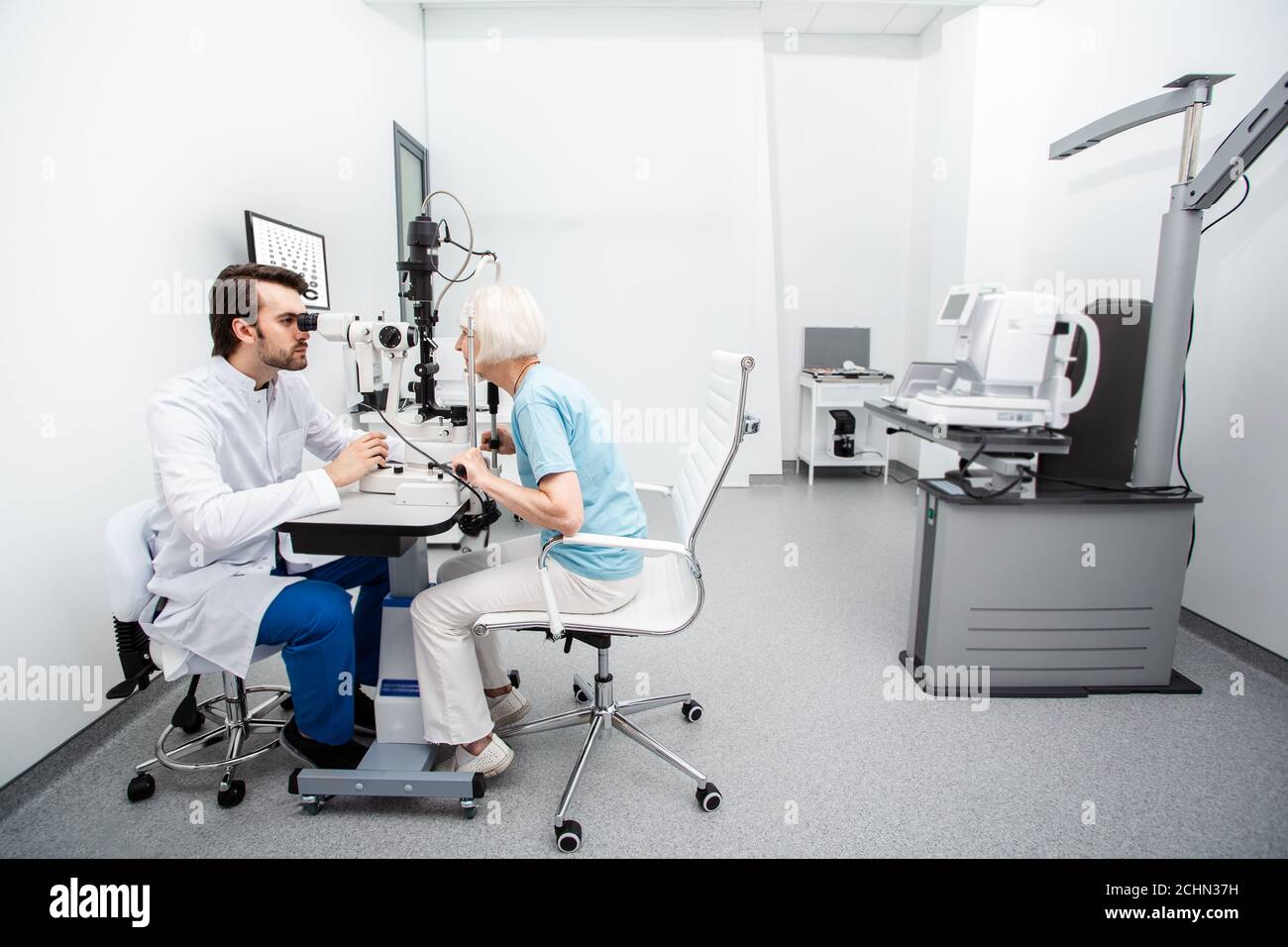 Optométriste et patient âgé pendant le diagnostic de la vue dans une clinique moderne. Examen des yeux et contrôle de la vision Banque D'Images