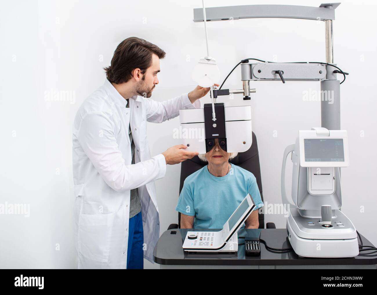 Optométriste sérieux expérimenté effectuant des tests sur site pour un patient utilisant un phoropter moderne dans une clinique médicale. Examen oculaire et diagnostic de la vision Banque D'Images