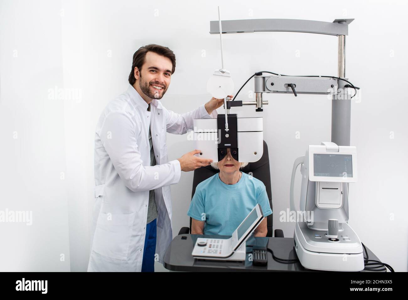 Optométriste sympathique effectuant des tests de vue pour un patient utilisant un phoropter moderne dans une clinique médicale. Examen oculaire et diagnostic de la vision Banque D'Images