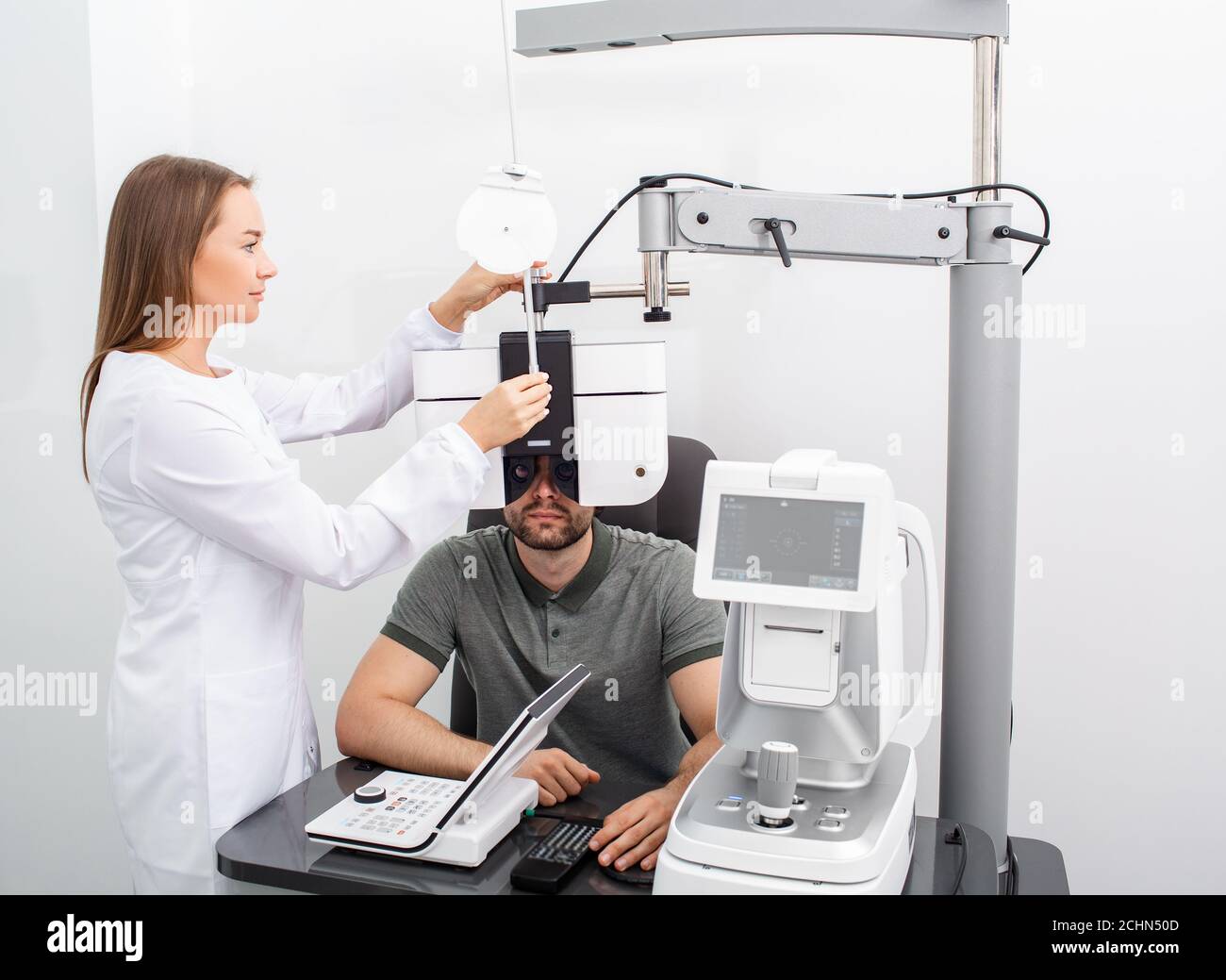 Femme ophtalmologiste faisant des tests de vue pour un homme beau patient utilisant un phoropter moderne dans une clinique médicale. adul pour l'examen oculaire et le diagnostic de la vision Banque D'Images