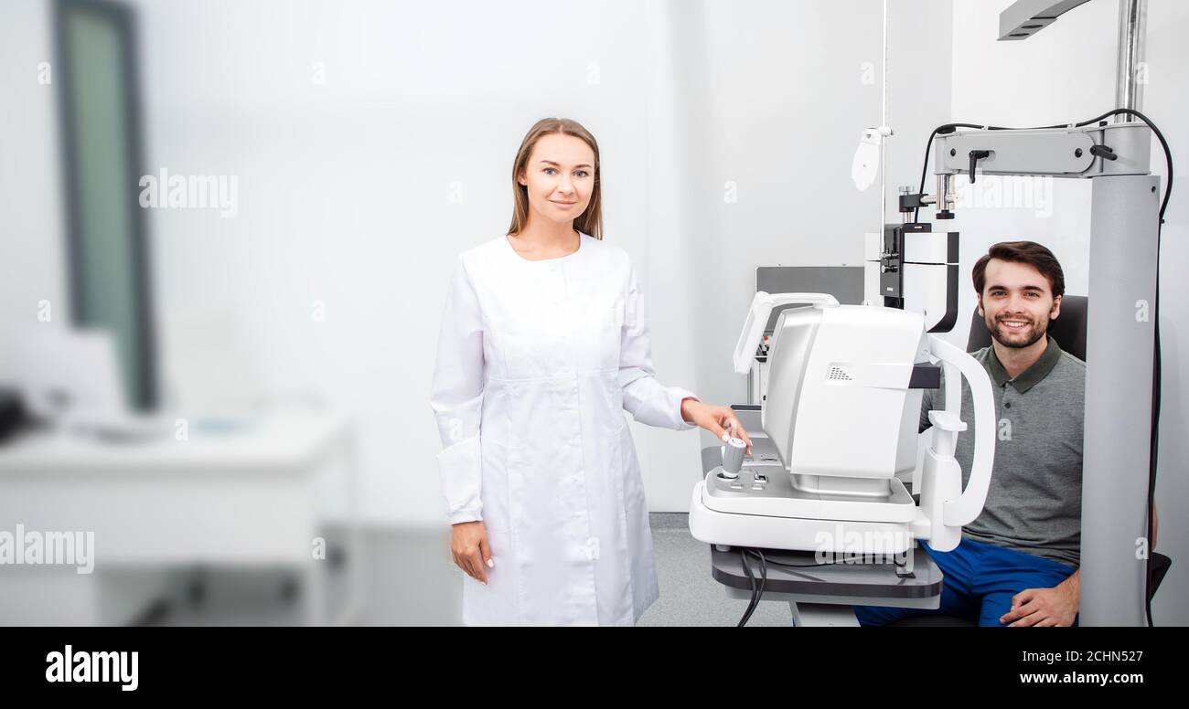 Portrait d'une belle femme ophtalmologiste avec un homme patient près de l'équipement ophtalmologique dans un bureau ophtalmologique moderne Banque D'Images