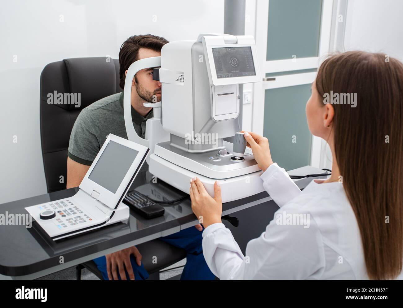 Femme ophtalmologiste à l'aide d'un auto-fractor calculer la correction de la vision d'un homme patient dans une clinique ophtalmologique moderne Banque D'Images