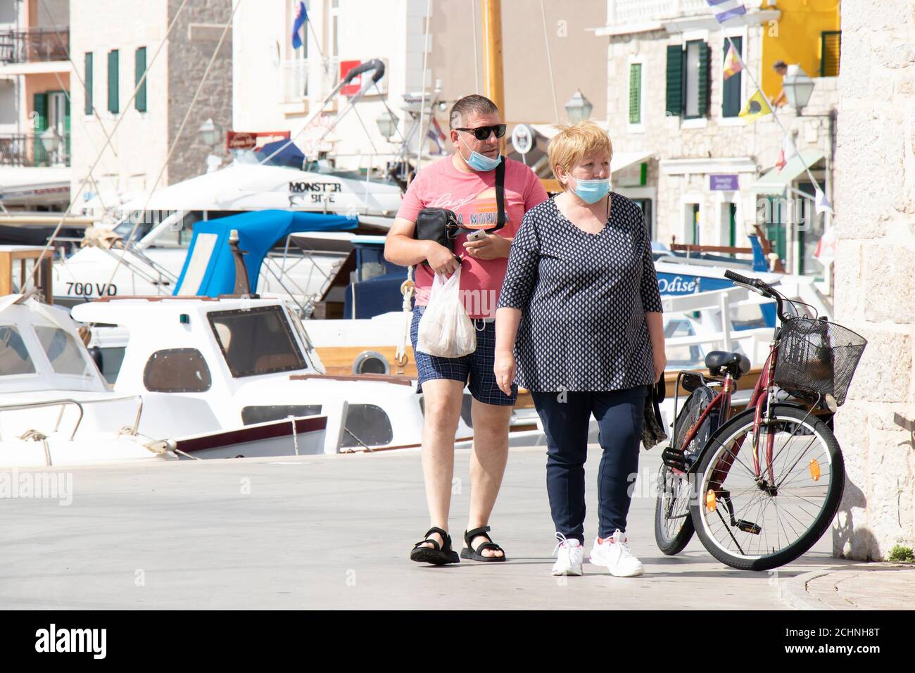 Vodice, Croatie - 1 septembre 2020 : couple mature en surpoids portant des masques chirurgicaux sur le front de mer d'une petite ville méditerranéenne Banque D'Images