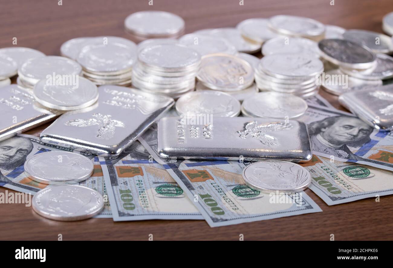 Gros plan des barres d'argent et des pièces d'argent et 100 dollars factures sur table en bois Banque D'Images