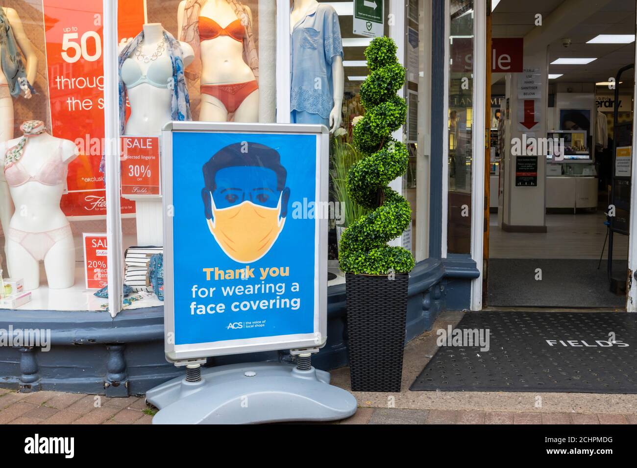 Panneau de bord de route à l'extérieur d'une entrée d'atelier demandant aux clients de porter un revêtement de visage à l'entrée. Sidmouth, ville côtière de Devon, sur la côte sud de l'Angleterre Banque D'Images