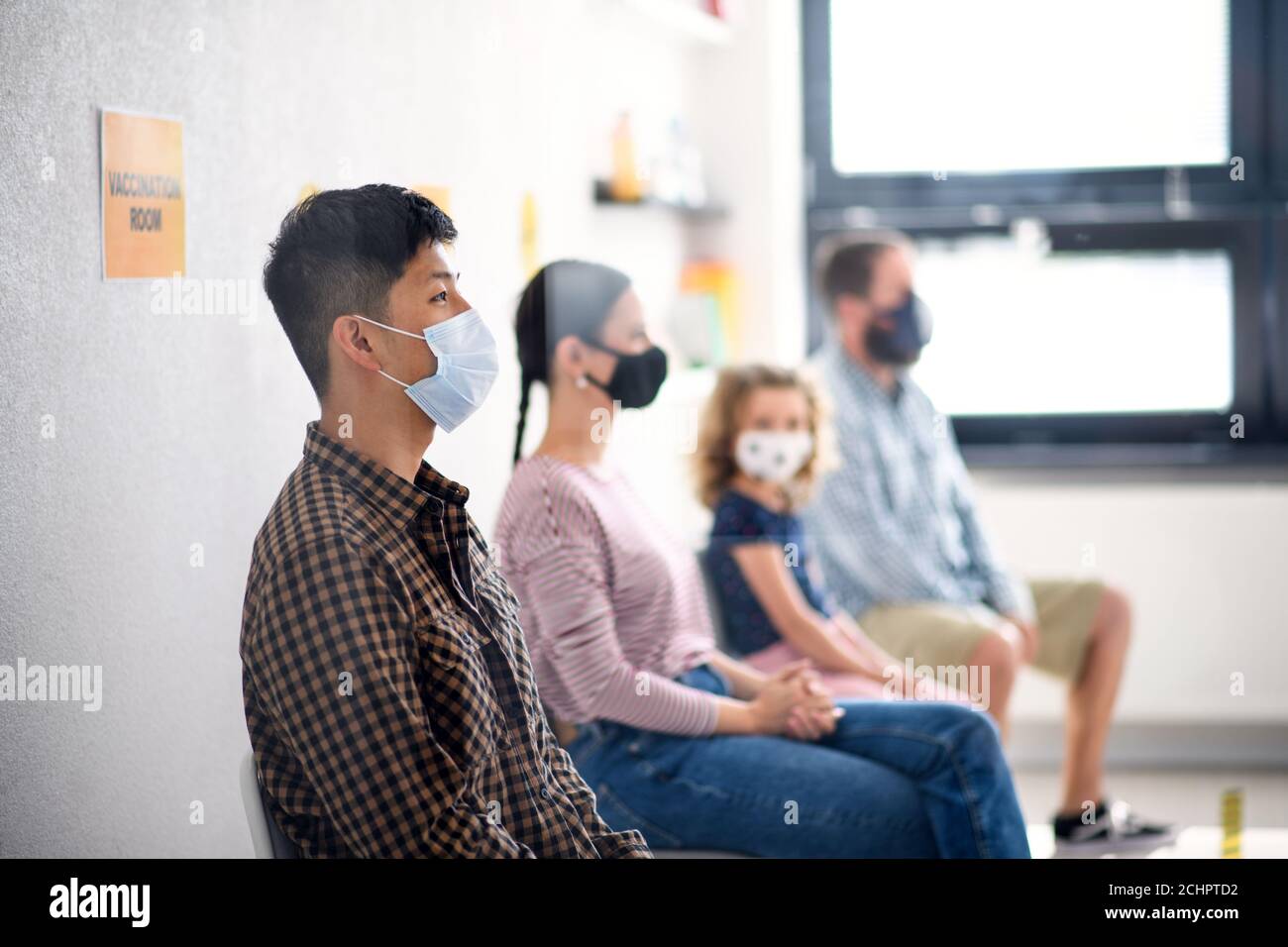 Personnes avec masques dans la salle d'attente à l'hôpital, coronavirus, covid-19 et concept de vaccination. Banque D'Images