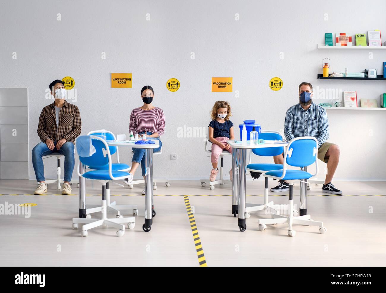 Personnes avec masques dans la salle d'attente à l'hôpital, coronavirus, covid-19 et concept de vaccination. Banque D'Images