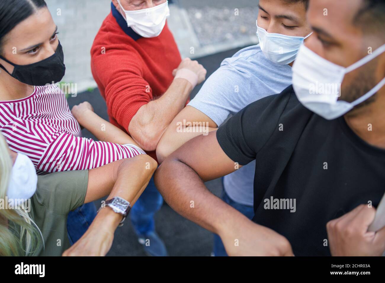 Groupe de personnes avec masques de visage coude bumping, coronavirus, covid-19 concept. Banque D'Images