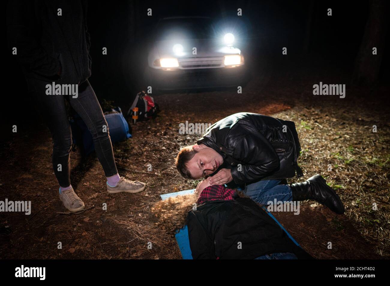 Formation de premiers soins sur le terrain. L'homme vérifie si la femme qui se trouve sur le sol respire. Une autre personne se trouve à proximité. Banque D'Images