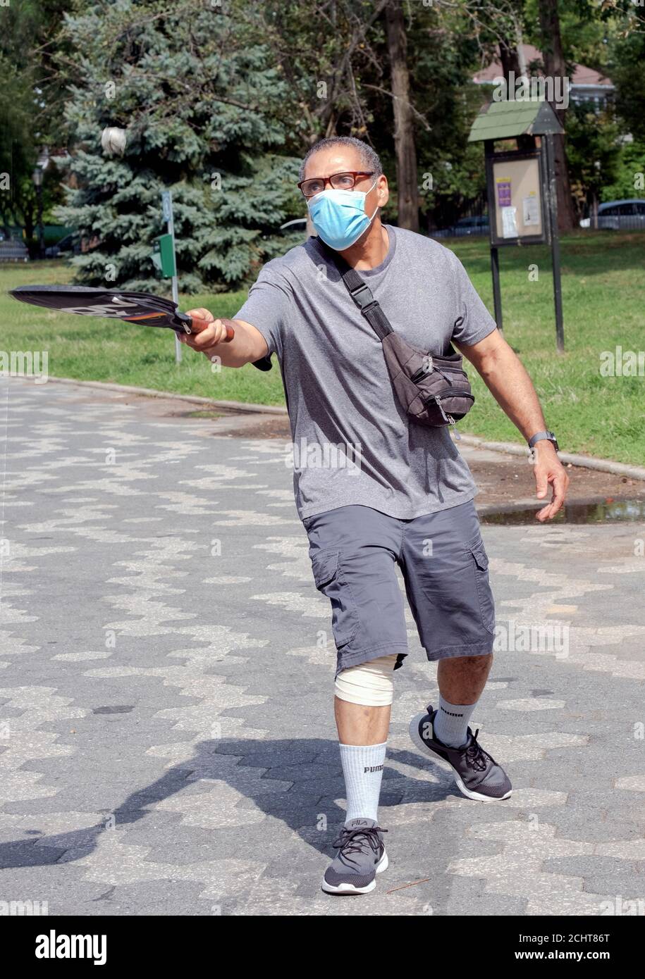 Un homme marche dans le parc tout en rebondissant une balle de son raquet de tennis. À Kissena Park, Flushing, New York. Banque D'Images