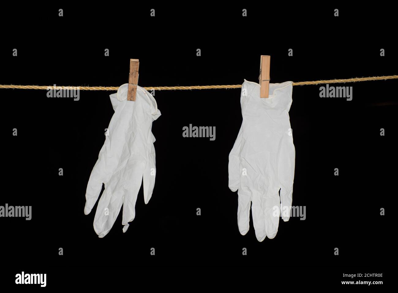 Les gants sont suspendus à la corde sur fond noir isolé Banque D'Images