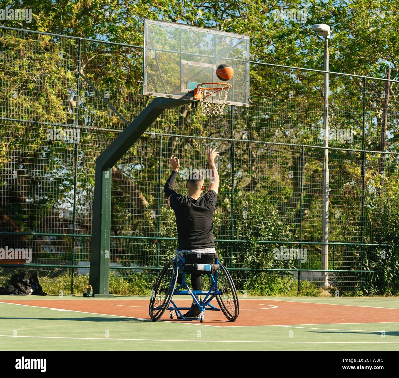 Jeune homme beau en fauteuil roulant jouant au basket-ball Banque D'Images