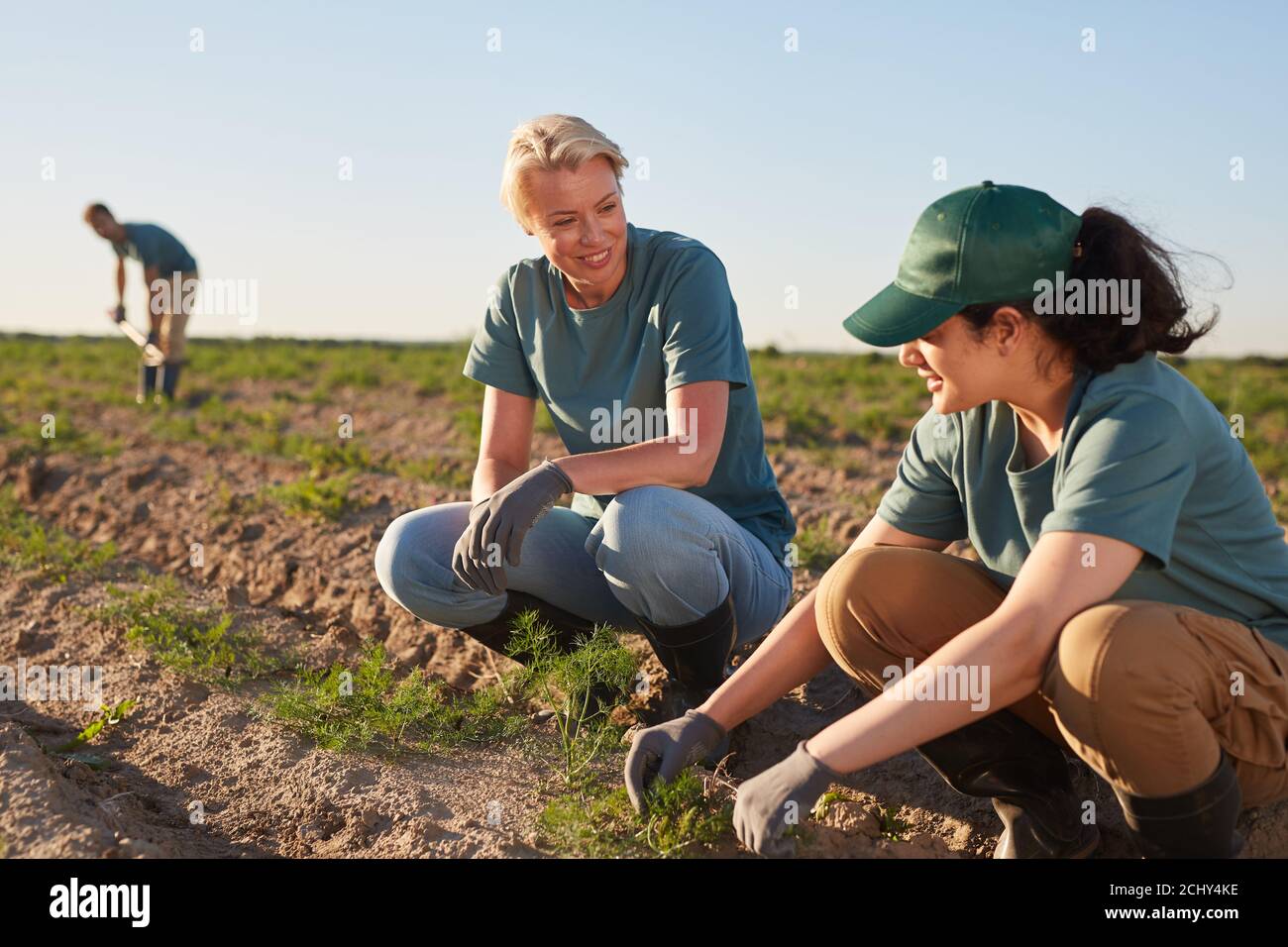 Portrait de deux jeunes femmes souriantes appréciant le travail à la plantation de légumes à l'extérieur éclairé par la lumière du soleil, l'espace de copie Banque D'Images