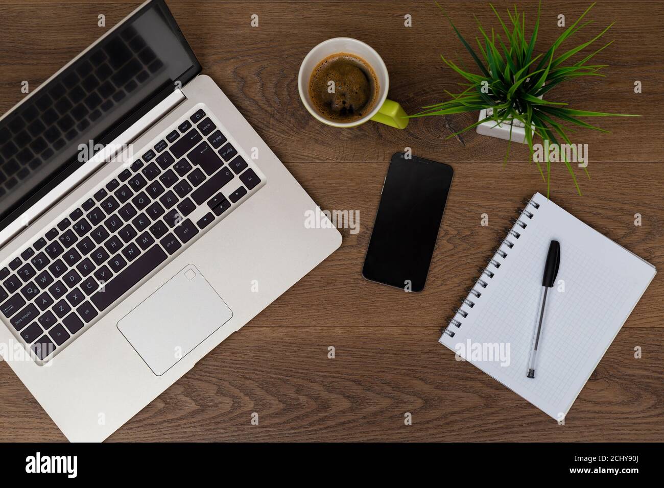 Vue de dessus de l'espace de travail. Table de travail avec ordinateur portable, téléphone portable, café, bloc-notes, stylo et plante avec espace vide fond pour le design. Vue sur la partie plate de dar Banque D'Images