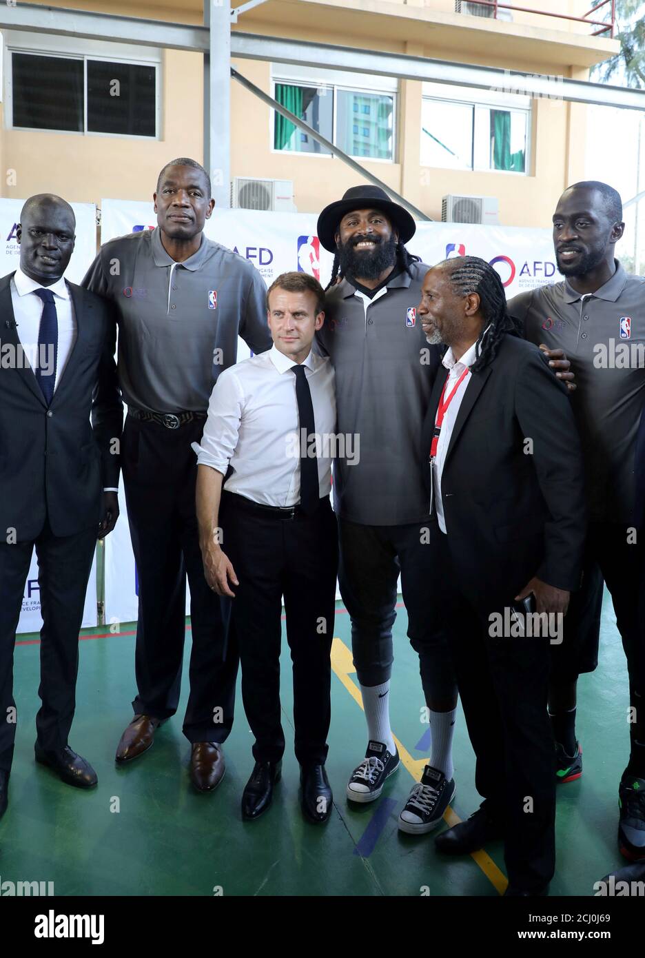 Le président français Emmanuel Macron et directeur général de la NBA  Afrique Amadou Gallo Fall (L) posent pour une photo avec d'anciens joueurs  de basket-ball pro de la NBA Afrique à l'école