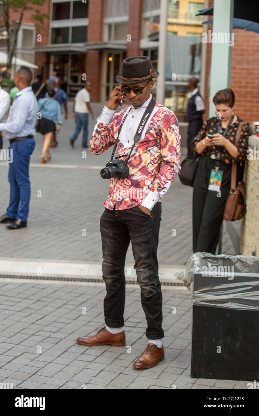 Homme africain bien habillé avec caméra à la semaine de la mode sud-africaine à Melrose Arch, Johannesburg, Afrique du Sud Banque D'Images