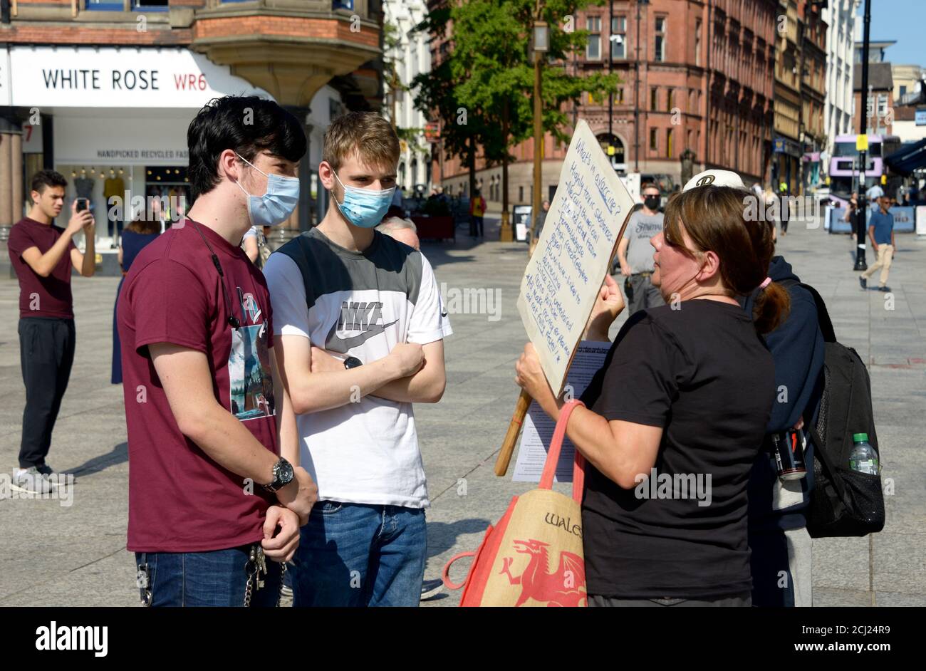 Un manifestant contre le vaccin, expliquant à deux jeunes hommes. Banque D'Images