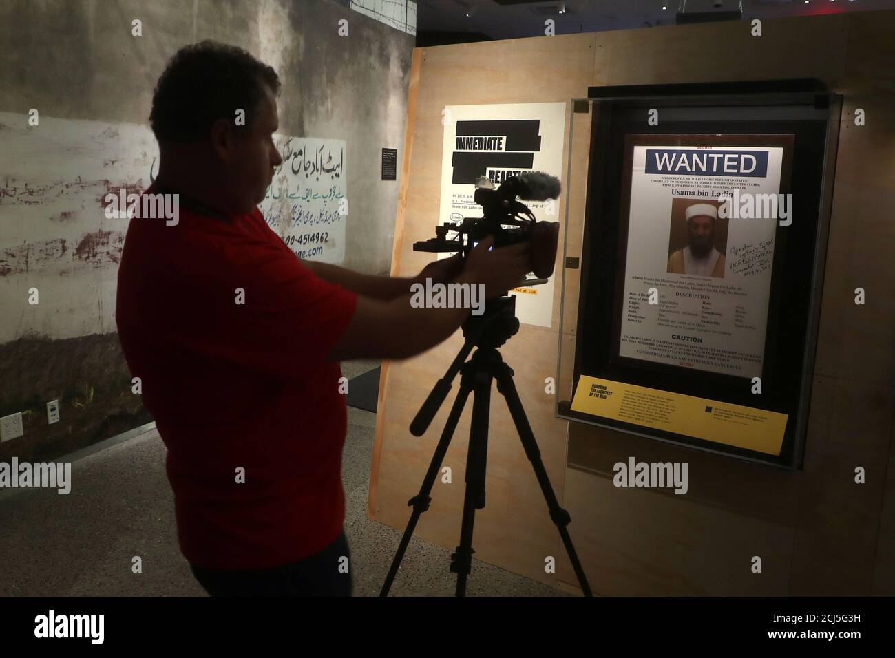 Un homme filme une affiche Oussama ben Laden voulait au 9/11 Museum dans une exposition intitulée « Revealed - The Hunt for Bin Laden » dans le quartier de Manhattan à New York, New York, États-Unis, le 7 novembre 2019. REUTERS/Carlo Allegri Banque D'Images
