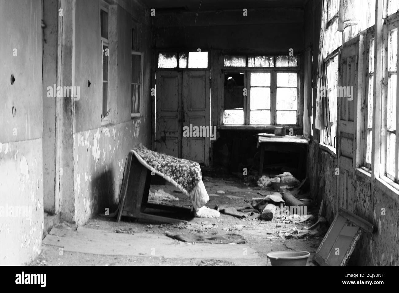 Photo en niveaux de gris d'un ancien bâtiment intérieur, meubles cassés, murs et fenêtres abîmés Banque D'Images