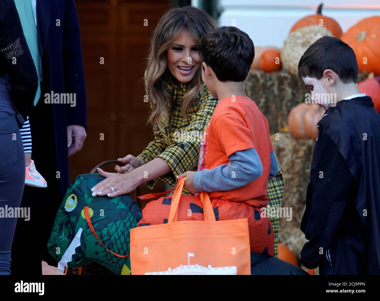 La première dame des États-Unis, Melania Trump, porte un costume de  dinosaure alors qu'elle et le président américain Donald Trump lui confient  des bonbons d'Halloween aux truck-or-treaters à la Maison Blanche à