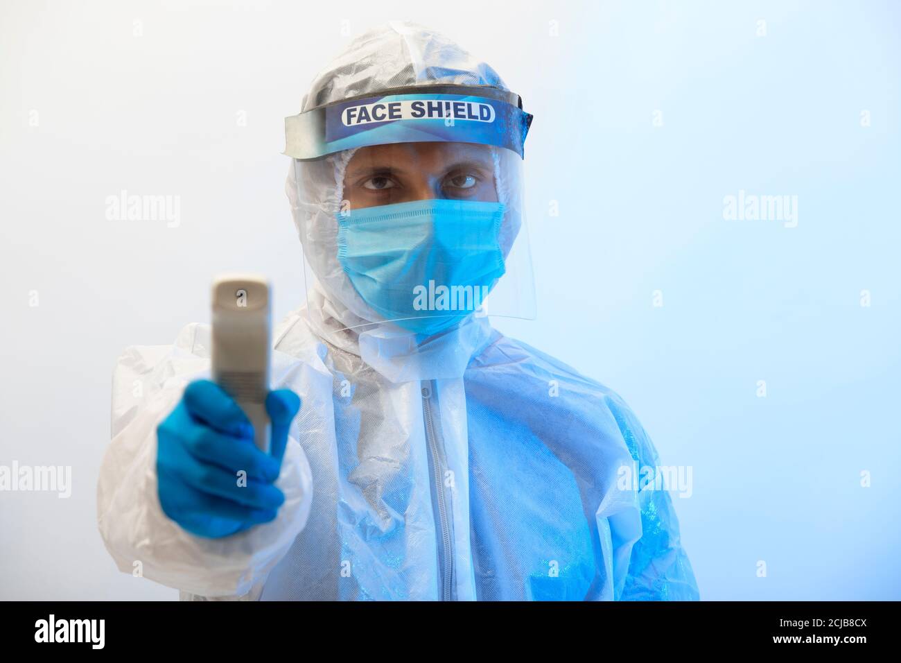 Homme dans un costume de protection avec un thermomètre infrarouge pistolet dans la main Banque D'Images