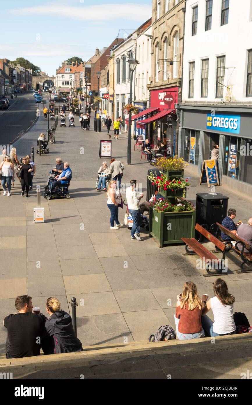 Un couple s'est assis sur les marches de l'hôtel de ville de Berwick en regardant Marygate à Berwick upon Tweed, Northumberland, Angleterre, Royaume-Uni Banque D'Images