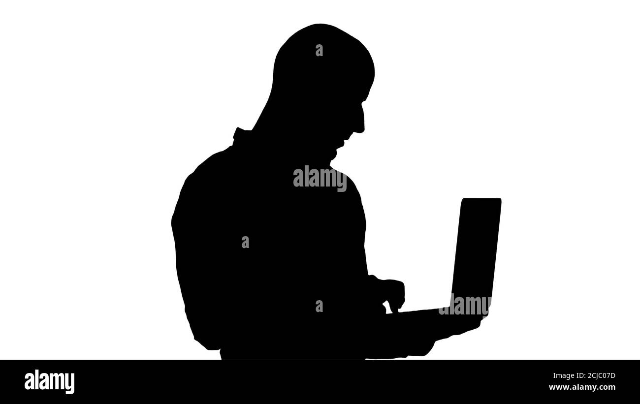 Silhouette Young homme d'affaires du Moyen-Orient, debout et dactylographiant sur un ordinateur portable en le tenant dans ses mains. Banque D'Images