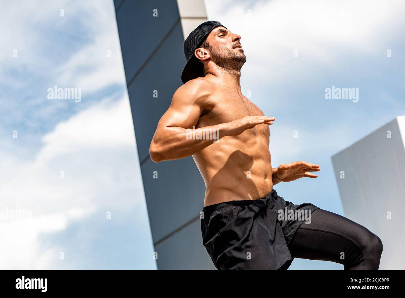Beau sport de forme homme faisant l'exercice de haut genou tapoter dehors sur le toit du bâtiment, concept d'entraînement à la maison Banque D'Images