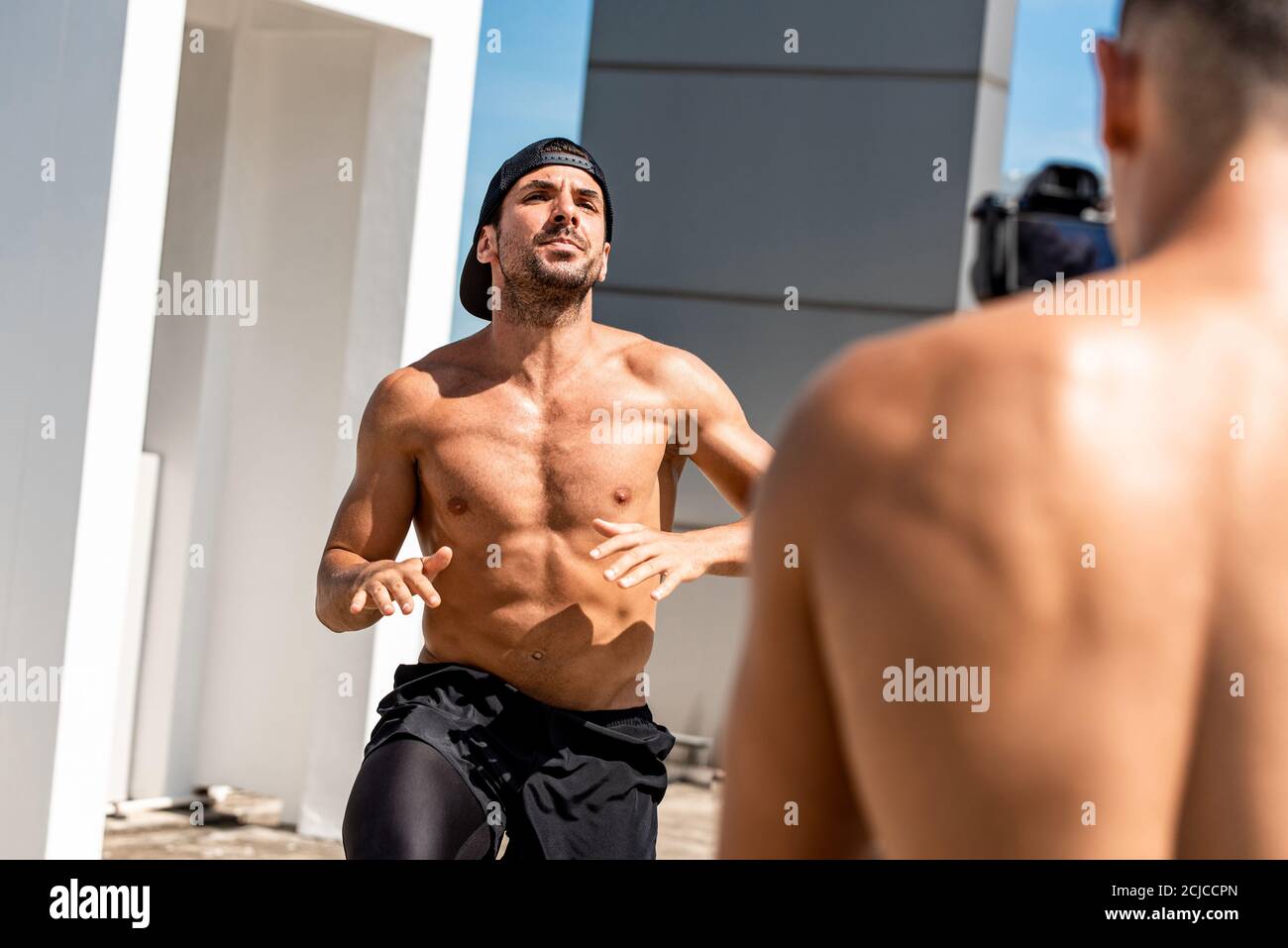 Homme musculaire influenceur d'exercice enregistrement vidéo clip ourdoors sur le toit, concept d'entraînement à la maison Banque D'Images