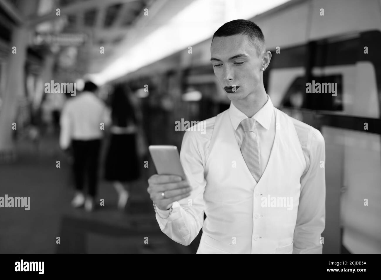 Jeune homme d'affaires androgyne beau utilisant le téléphone dans la ville Banque D'Images