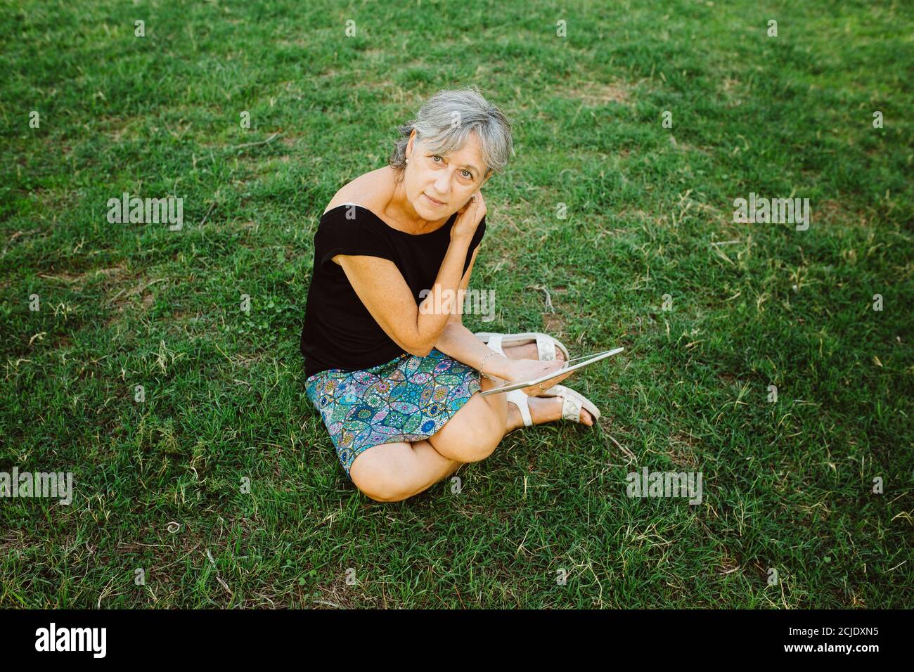 Femme âgée discutant en ligne avec sa tablette dans un parc Banque D'Images